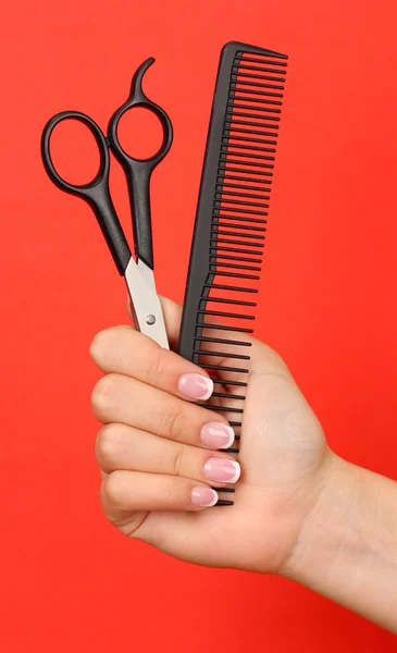 Color comb and scissors in female hand on color background — Stock Photo, Image