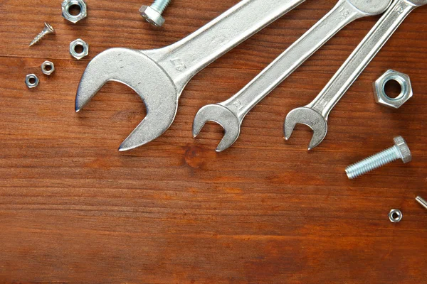 Śruby, wkręty, nakrętki i klucze na drewnianym stole — Zdjęcie stockowe