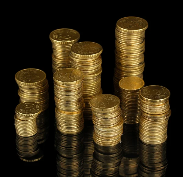 Many coins in columns isolated on black — Stock Photo, Image