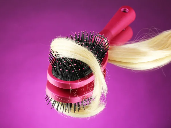 Peine cepillo con pelo sobre fondo púrpura — Foto de Stock