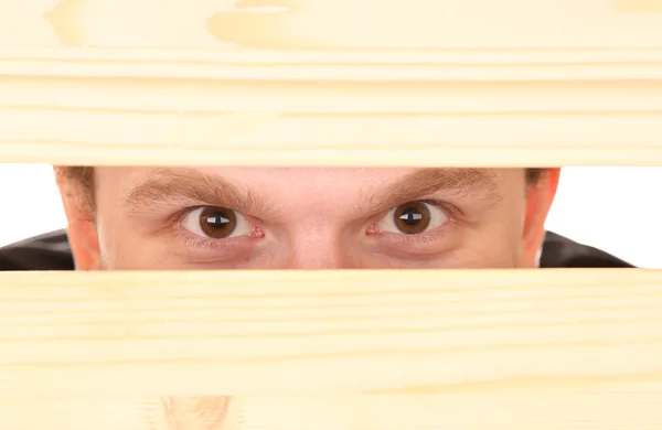 Hombre ojos mirando a través de agujero en escritorio de madera —  Fotos de Stock