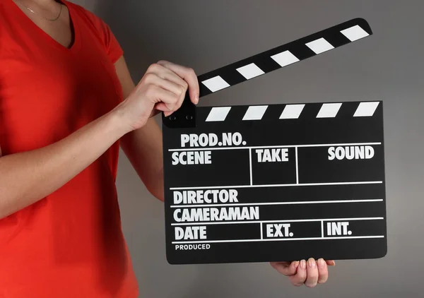 Movie production clapper board in hands on grey background — Stock Photo, Image