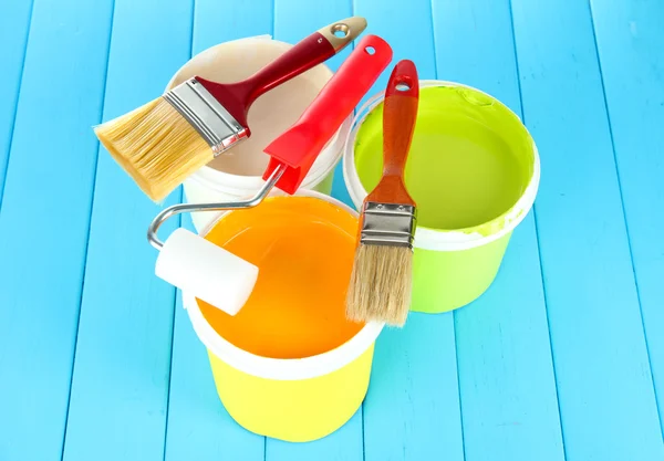 Set para pintar: macetas, pinceles, rodillo de pintura sobre mesa de madera azul —  Fotos de Stock