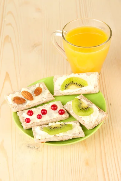 Tasty canapes with cheese, kiwi and cranberry, almond, on color plate, on wooden background — Stock Photo, Image