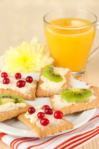 Läckra tilltugg med ost och kiwi, tranbär, på färgplåt, på trä bakgrund — Stockfoto