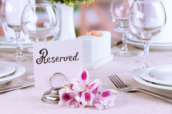 Reserved sign on restaurant table with empty dishes and glasses — Stock Photo, Image