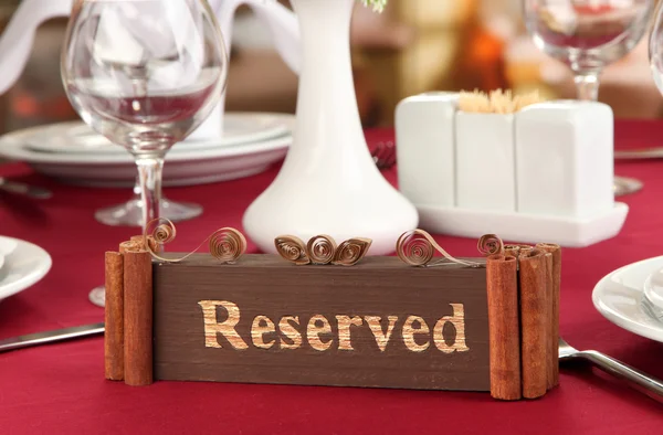 Reserved sign on restaurant table with empty dishes and glasses — Stock Photo, Image