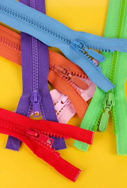 Multicolored zippers on yellow background — Stock Photo, Image