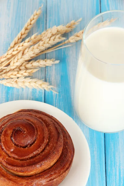 Rotolo di pane e bicchiere di latte su sfondo blu di legno — Foto Stock