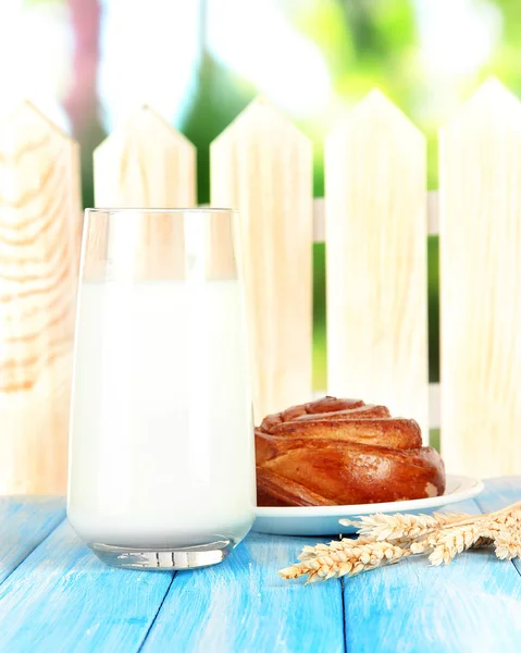 Bread roll and glass of milk on blue wooden background — Stock Photo, Image