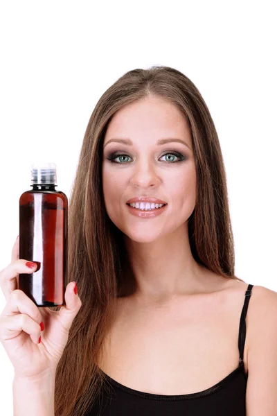Женщина с длинными волосами, держащая бутылку шампуня, изолированная на белом — стоковое фото