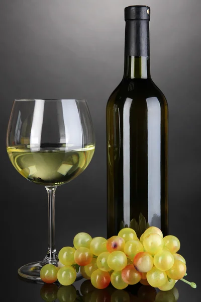 Copa de vino blanco y botella de vino sobre fondo gris — Foto de Stock