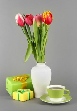 Hediyeler ve gri arka plan üzerinde çay ile kova güzel laleler