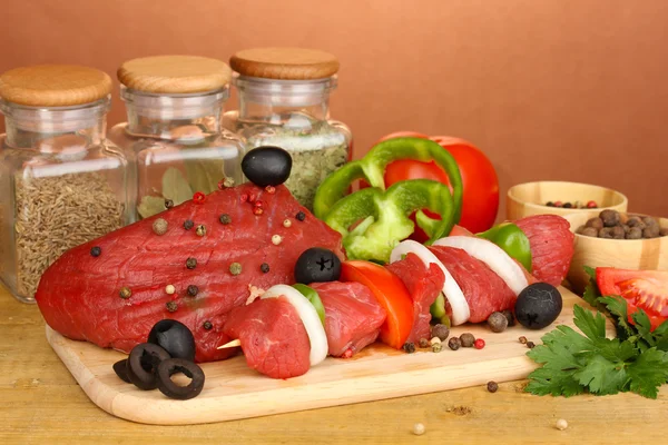 Raw beef meat marinated with herbs and spices on wooden table on brown background — Stock Photo, Image