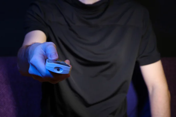Mann hält eine Fernbedienung in der Hand, auf dunklem Hintergrund — Stockfoto