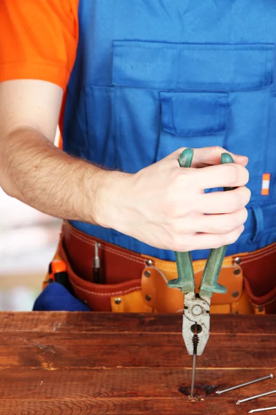 Builder sort les ongles avec plierson sur fond de pièce — Photo