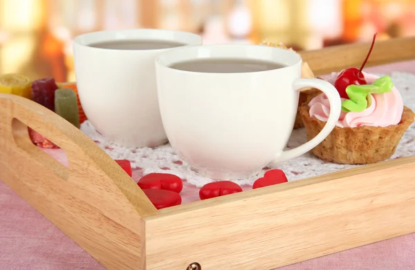 Kopjes thee met gebak op houten lade op tafel in café — Stockfoto