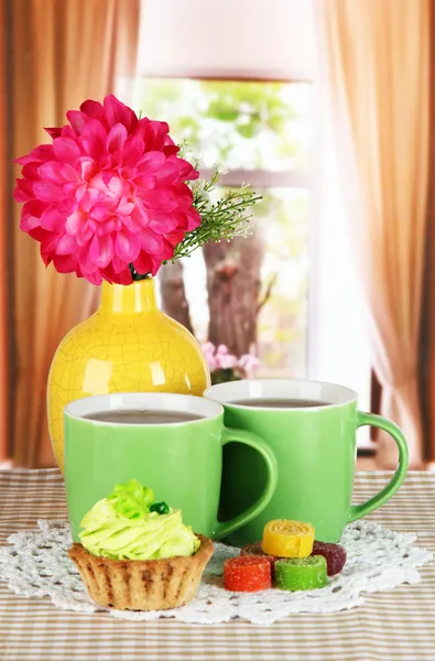 Чашки чая с тортом, конфеты и цветы на столе в номере — стоковое фото