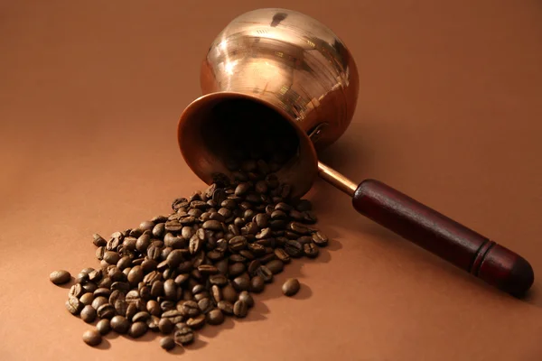 Cafetera con granos de café sobre fondo marrón — Foto de Stock