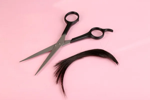 Pieces of hair cut with scissors on pink background — Stock Photo, Image