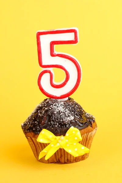 Birthday cupcake with chocolate frosting on yellow background — Stock Photo, Image