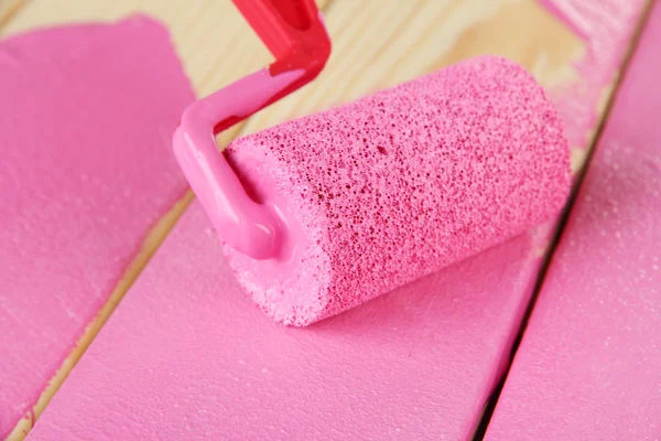Pincel rodillo de pintura con pintura rosa, sobre fondo de madera — Foto de Stock