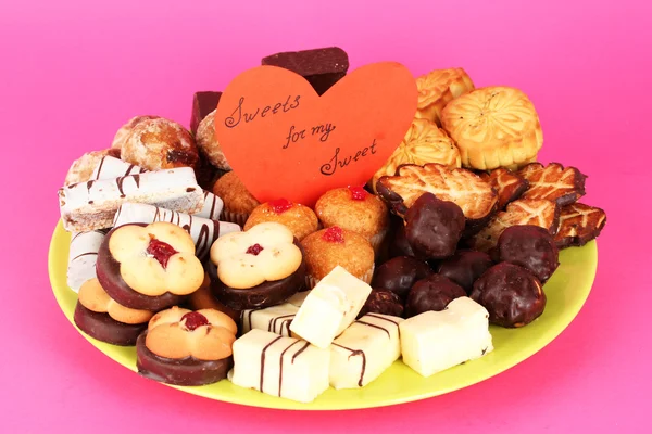 Sweet cookies on plate with valentine card on pink background Stock Photo