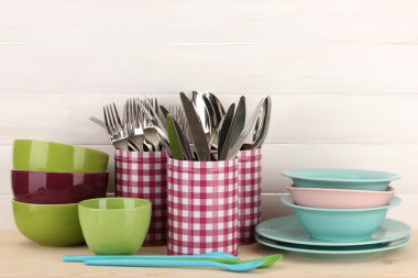 Cups, bowls nd other utensils in metal containers isolated on light background