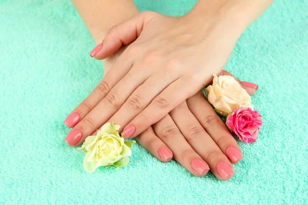 Mani donna con manicure rosa e fiori, su sfondo colore — Foto Stock
