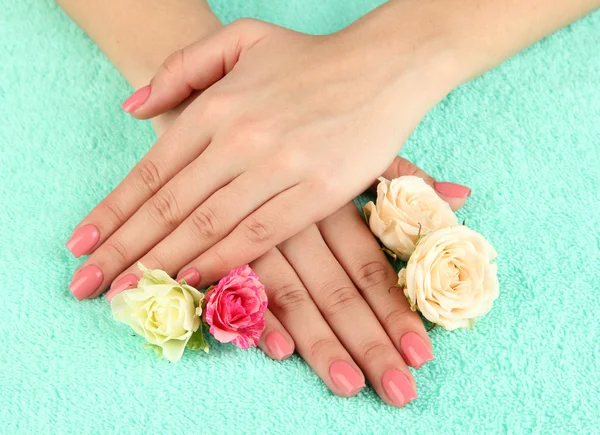 Kvinna händer med rosa manikyr och blommor, färg bakgrunden — Stockfoto