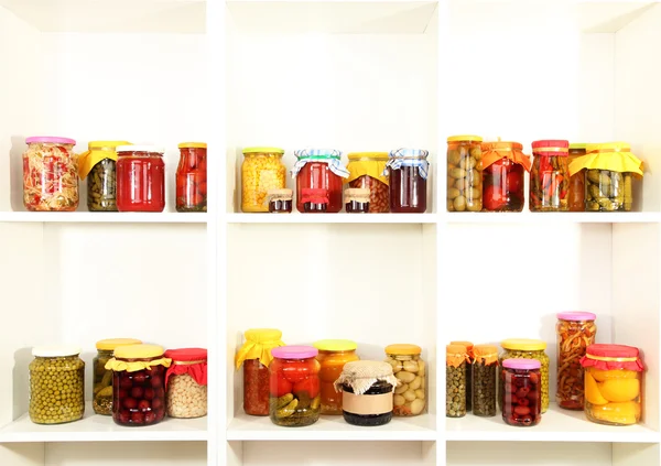 Different conservations on white shelves — Stock Photo, Image