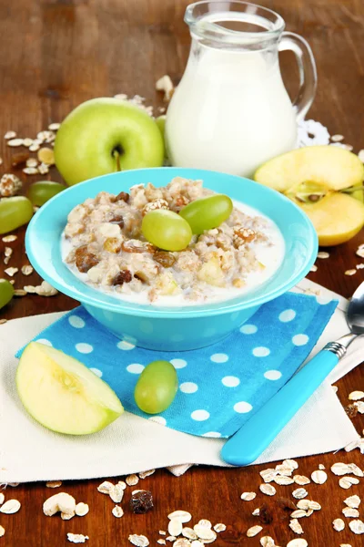 Harina de avena útil en un tazón con fruta en una mesa de madera — Foto de Stock