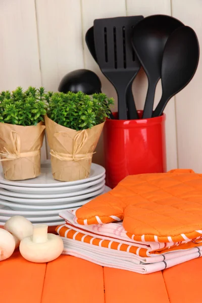 Kitchen settings: utensil, potholders, towels and else on wooden table — Stock Photo, Image