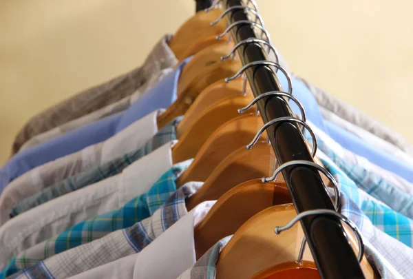 Men's shirts on hangers on beige background — Stock Photo, Image