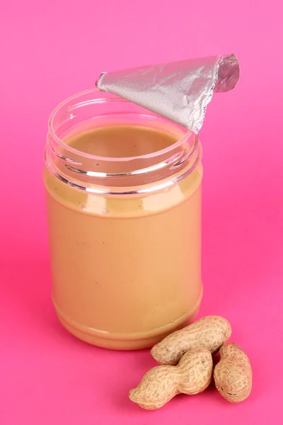 Deliciosa manteiga de amendoim em frasco aberto de amendoim perto de fundo rosa — Fotografia de Stock