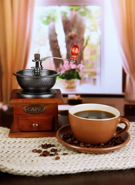 Kopp kaffe med halsduk och kaffe mal på bordet i rummet — Stockfoto