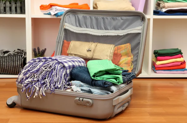 Open grijs koffer met kleding op kamer — Stockfoto