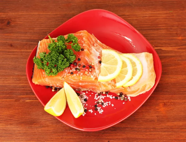 Fresh salmon fillet with herbals and lemon slices on plate,on wooden background — Stock Photo, Image