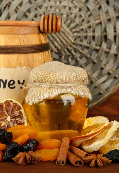 Jar of honey, wooden barrel, drizzler and dried fruits on wooden background — Stock Photo, Image