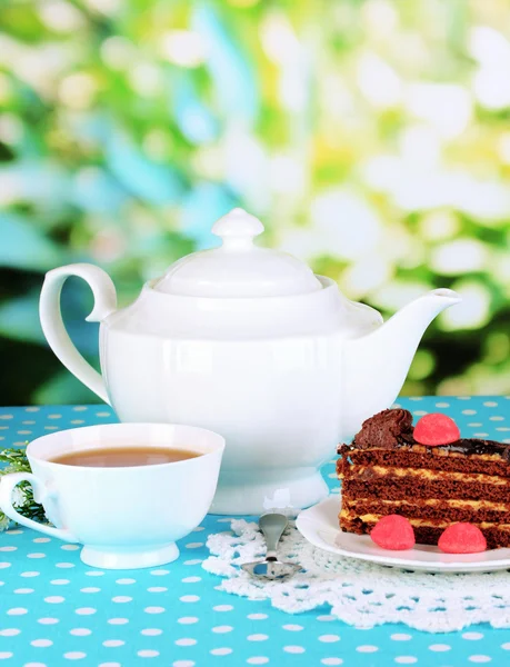 Tekanna, kopp te och läcker tårta på naturliga bakgrund — Stockfoto