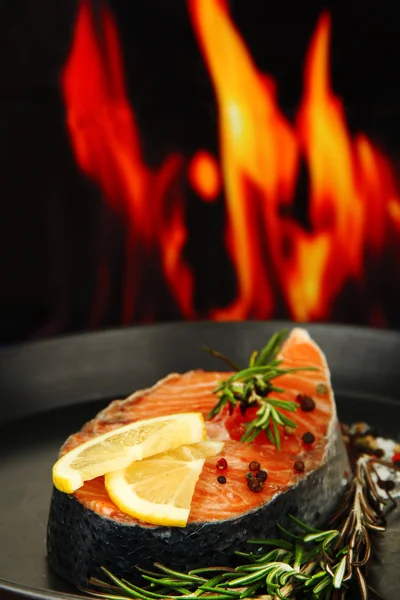 Свежий лосось стейк на сковороде, на огненном фоне, закрыть Стоковое Изображение