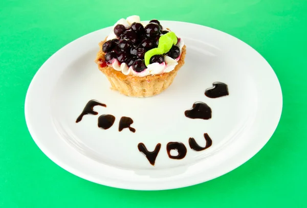 Sweet cake with blackberry and chocolate sauce on plate, on color background — Stock Photo, Image