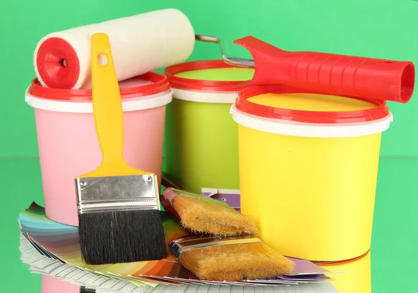 Set for painting: paint pots, brushes, paint-roller, palette of colors on green background — Stock Photo, Image