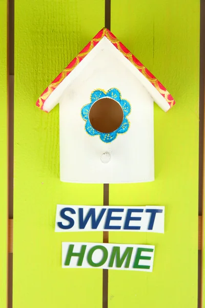 Decorative nesting box and sign on color background — Stock Photo, Image