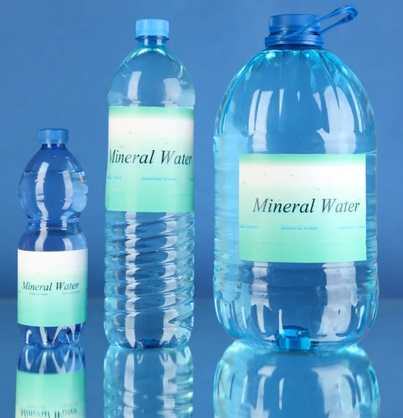 Different water bottles with label on blue background — Stock Photo, Image