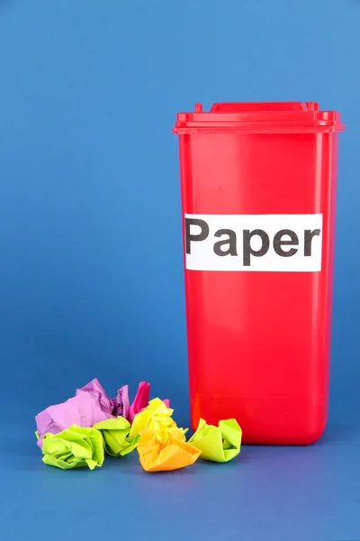 Recycling bin with papers on blue background — Stock Photo, Image