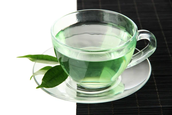 Διαφανής φλιτζάνι πράσινο τσάι σε χαλί μπαμπού, που απομονώνονται σε λευκό — Φωτογραφία Αρχείου