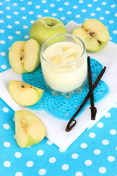 Iogurte delicioso em vidro com maçã na toalha de mesa azul — Fotografia de Stock