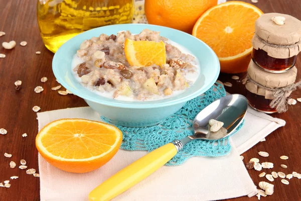 Useful oatmeal in bowl with fruit on wooden table close-up — Stock Photo, Image