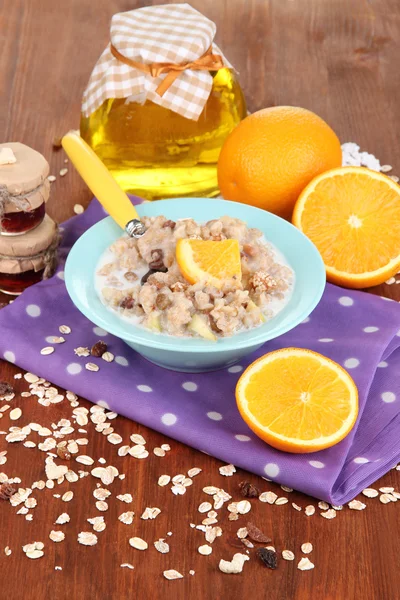 Harina de avena útil en un tazón con fruta en una mesa de madera — Foto de Stock